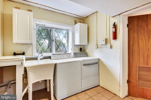 laundry area featuring separate washer and dryer, cabinets, and light tile patterned flooring