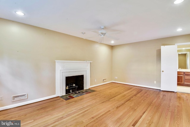 unfurnished living room featuring sink, a fireplace, light hardwood / wood-style floors, and ceiling fan