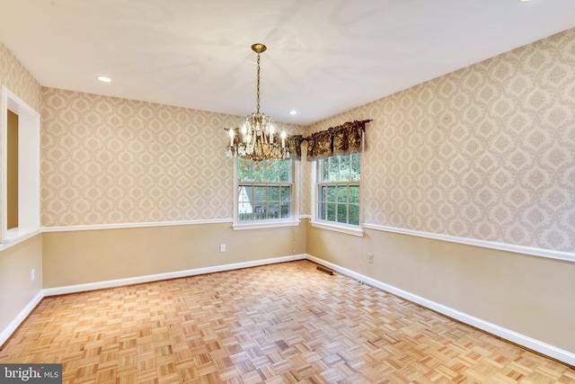 spare room featuring a notable chandelier and light parquet flooring