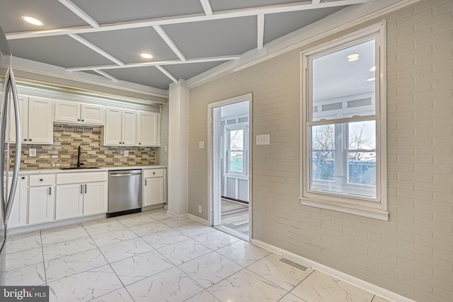 kitchen with sink, white cabinets, dishwasher, and brick wall