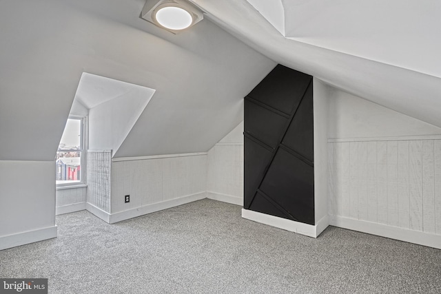 additional living space featuring vaulted ceiling and light colored carpet