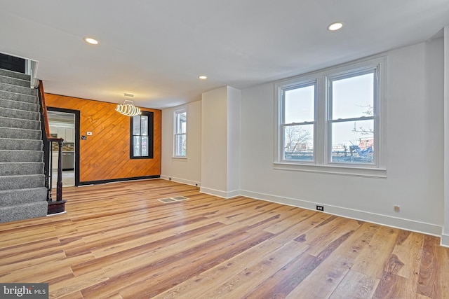 unfurnished living room with light hardwood / wood-style floors and wood walls