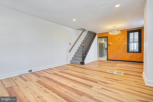 unfurnished room featuring light wood-type flooring and wood walls