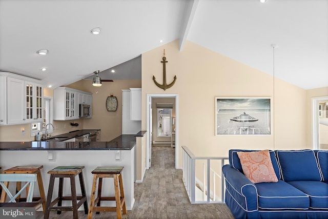 kitchen featuring sink, white cabinetry, lofted ceiling with beams, a kitchen breakfast bar, and kitchen peninsula