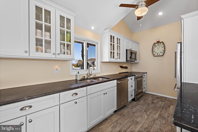 kitchen featuring lofted ceiling, sink, dark stone countertops, stainless steel appliances, and white cabinets