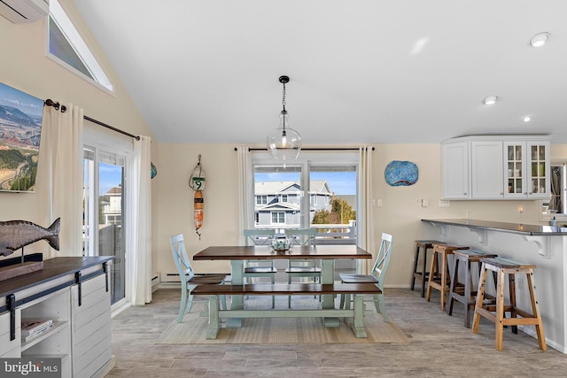 dining space featuring lofted ceiling, plenty of natural light, light wood-type flooring, and an AC wall unit