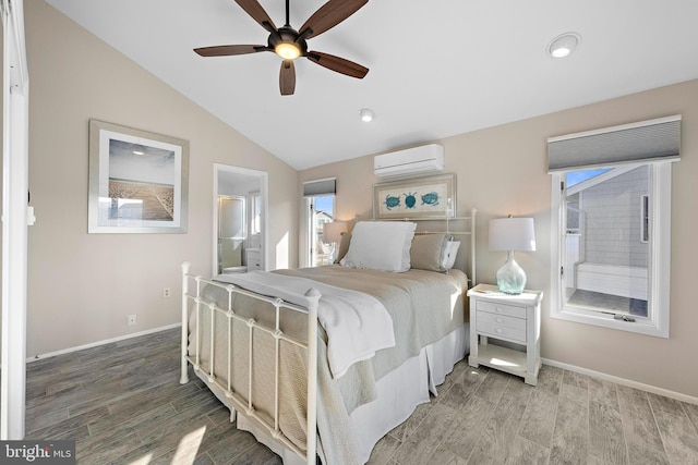 bedroom with lofted ceiling, ensuite bath, a wall mounted AC, hardwood / wood-style flooring, and ceiling fan