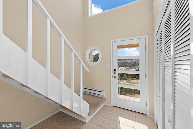 tiled entryway featuring a towering ceiling and a baseboard heating unit