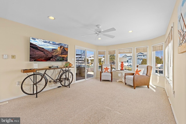 sitting room featuring ceiling fan, a healthy amount of sunlight, and carpet