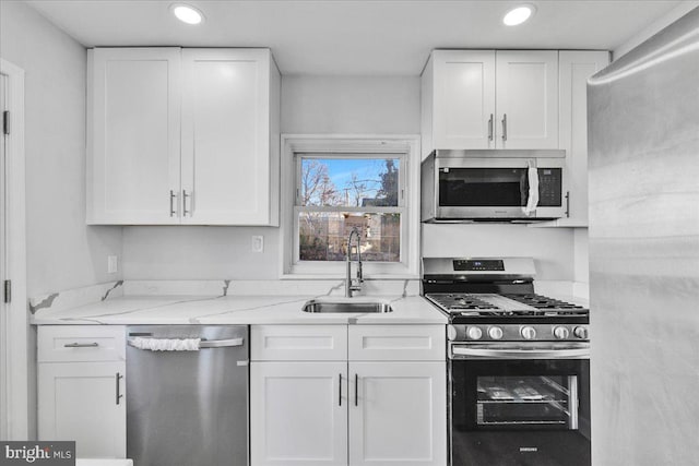 kitchen featuring light stone countertops, white cabinetry, appliances with stainless steel finishes, and sink