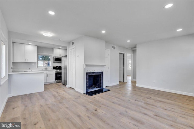 kitchen with sink, white cabinetry, stainless steel appliances, light hardwood / wood-style floors, and decorative backsplash