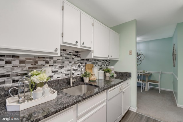 kitchen with sink, white cabinets, white dishwasher, and dark stone counters