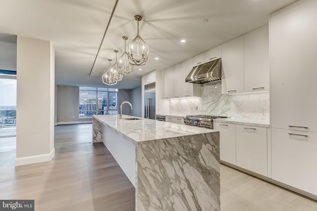 kitchen with white cabinetry, hanging light fixtures, light stone counters, and a spacious island