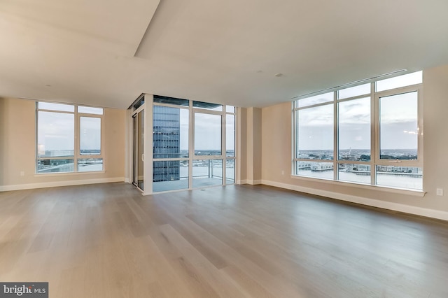 empty room featuring wood-type flooring, a water view, and a healthy amount of sunlight