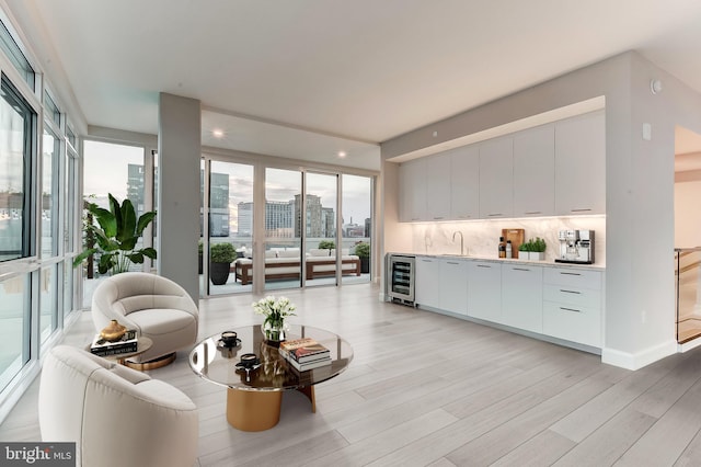 living room with light hardwood / wood-style floors, wet bar, and beverage cooler