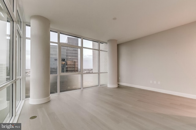 empty room featuring a wall of windows and light hardwood / wood-style floors