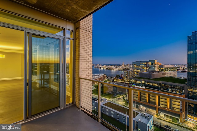 balcony at dusk featuring a water view