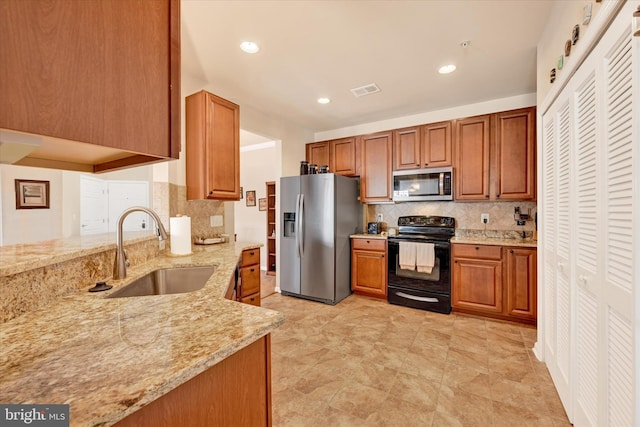 kitchen featuring appliances with stainless steel finishes, sink, backsplash, and light stone counters