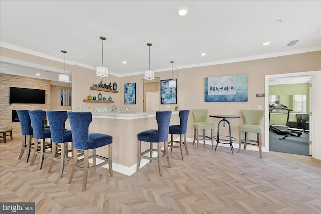 kitchen featuring ornamental molding, light parquet flooring, decorative light fixtures, and a breakfast bar area