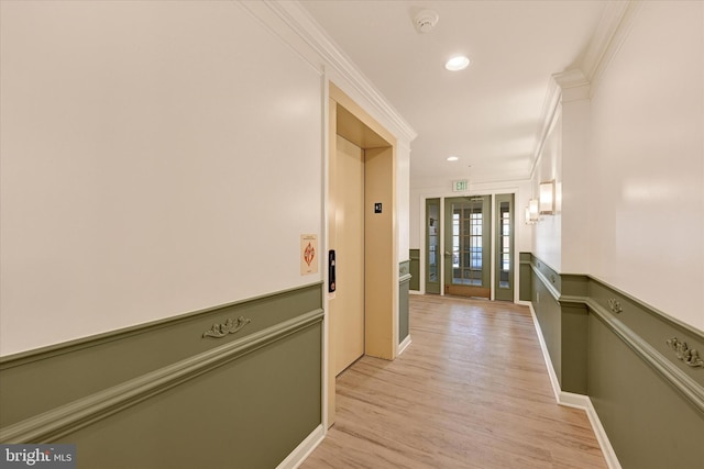 hallway with ornamental molding, elevator, and light hardwood / wood-style floors