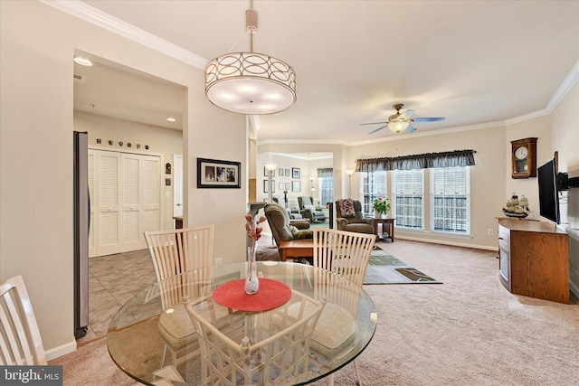 dining area with crown molding, light colored carpet, and ceiling fan