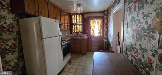 kitchen featuring white refrigerator, ornamental molding, radiator, and range