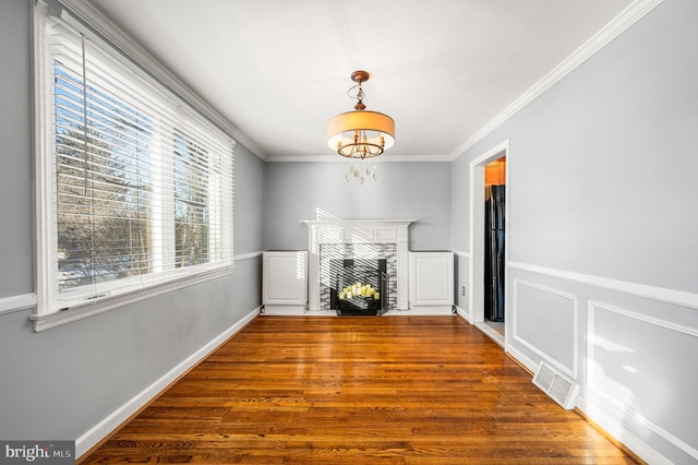 unfurnished living room with crown molding, an inviting chandelier, and hardwood / wood-style floors