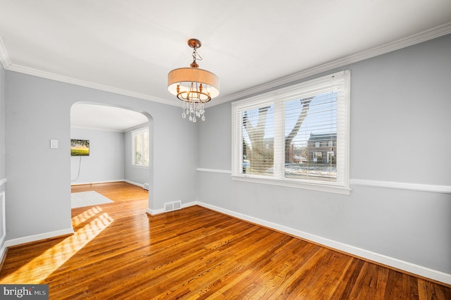 unfurnished dining area featuring crown molding, hardwood / wood-style flooring, and an inviting chandelier