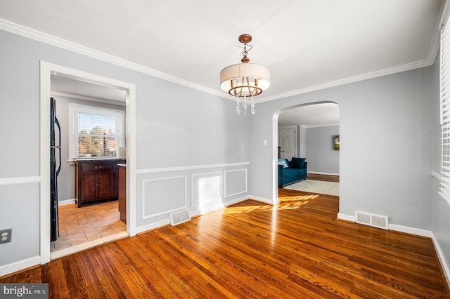 unfurnished dining area featuring crown molding, a chandelier, and light wood-type flooring