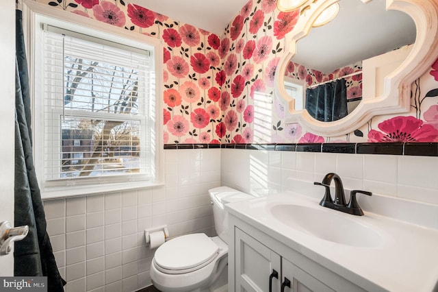 bathroom with vanity, toilet, and tile walls