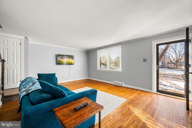 living room with hardwood / wood-style flooring, crown molding, and plenty of natural light