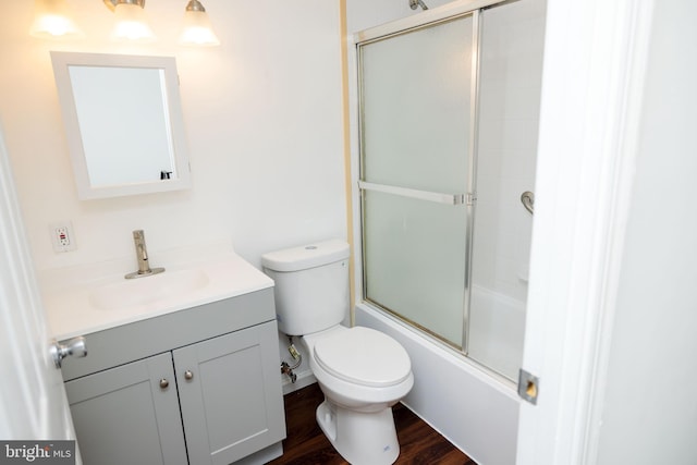 full bathroom featuring bath / shower combo with glass door, vanity, toilet, and hardwood / wood-style floors