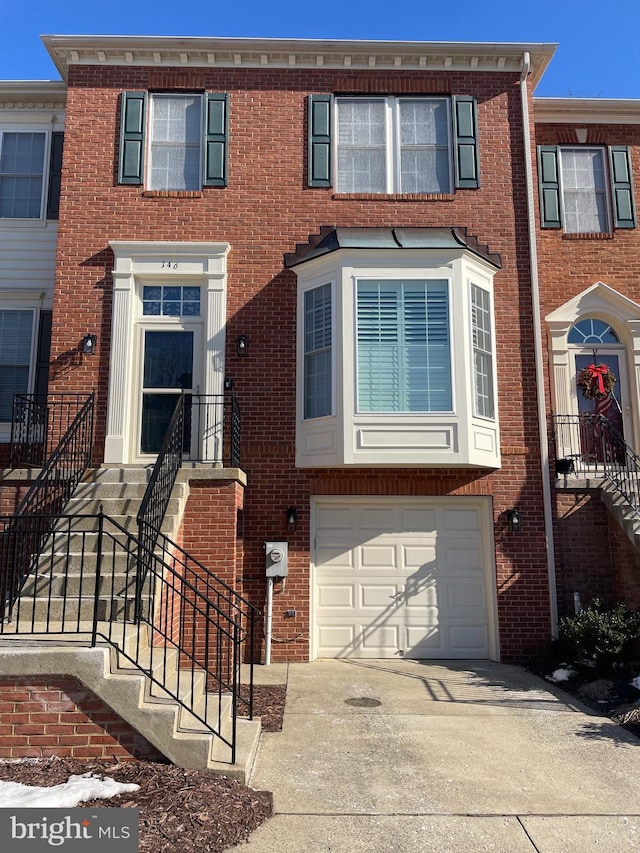 townhome / multi-family property featuring a garage, brick siding, and driveway