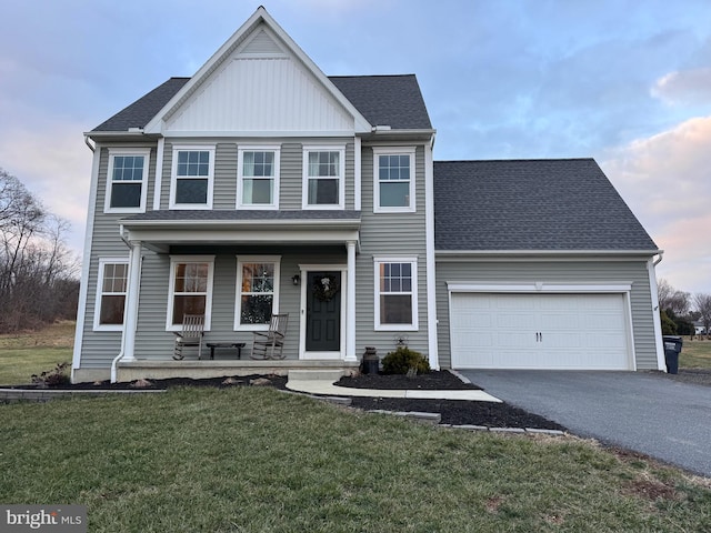 view of front of property featuring a garage, a lawn, and covered porch