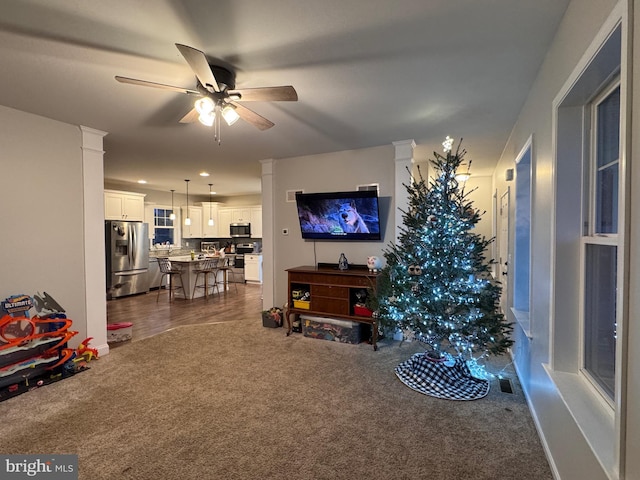 carpeted living room featuring ceiling fan and ornate columns