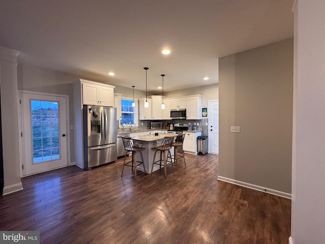 kitchen with a breakfast bar, pendant lighting, white cabinetry, a center island, and stainless steel appliances