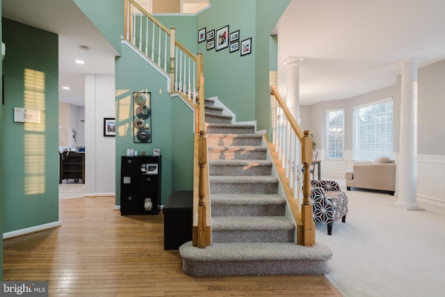 stairs with hardwood / wood-style floors and ornate columns