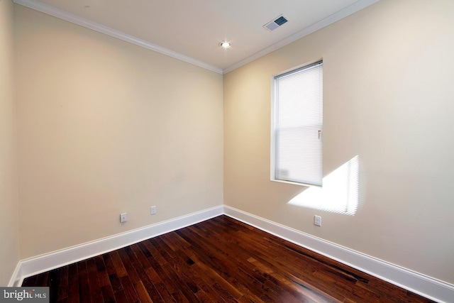 spare room with visible vents, a healthy amount of sunlight, crown molding, baseboards, and dark wood finished floors