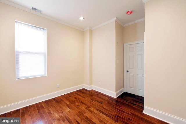 empty room featuring dark wood finished floors, visible vents, crown molding, and baseboards