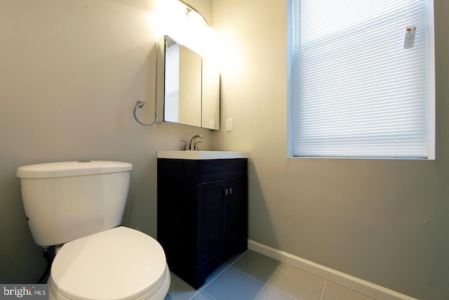 half bath with tile patterned flooring, toilet, vanity, and baseboards