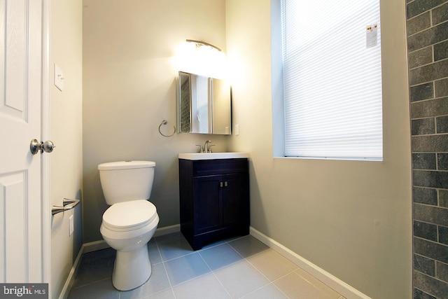 half bath with tile patterned floors, toilet, vanity, and baseboards