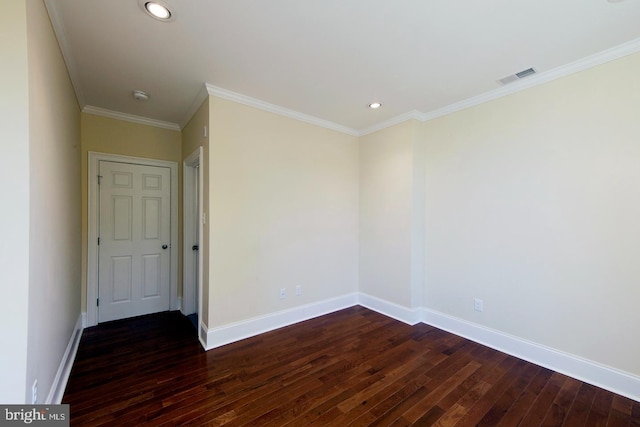 spare room featuring dark wood finished floors, crown molding, baseboards, and visible vents