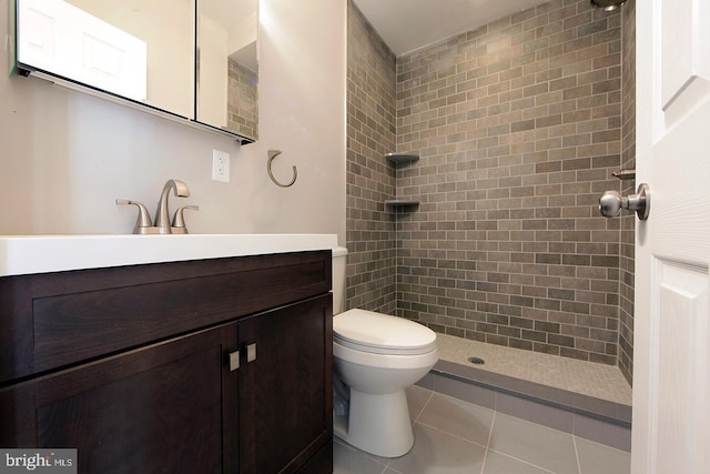 full bath featuring a tile shower, toilet, tile patterned floors, and vanity