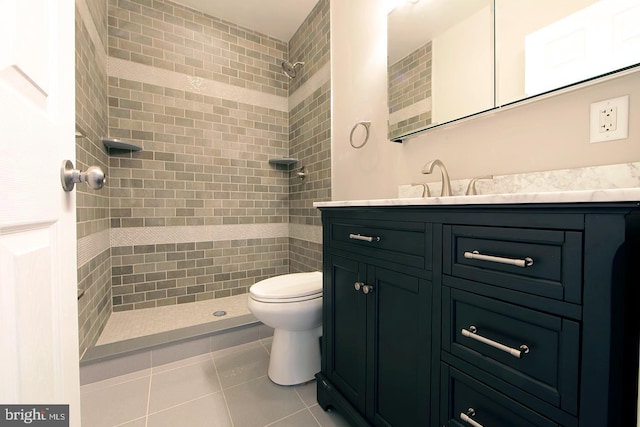 full bathroom featuring vanity, toilet, tile patterned flooring, and tiled shower