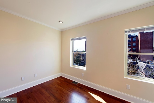 empty room featuring visible vents, baseboards, dark wood finished floors, and crown molding