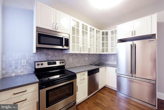 kitchen with a sink, glass insert cabinets, tasteful backsplash, and stainless steel appliances