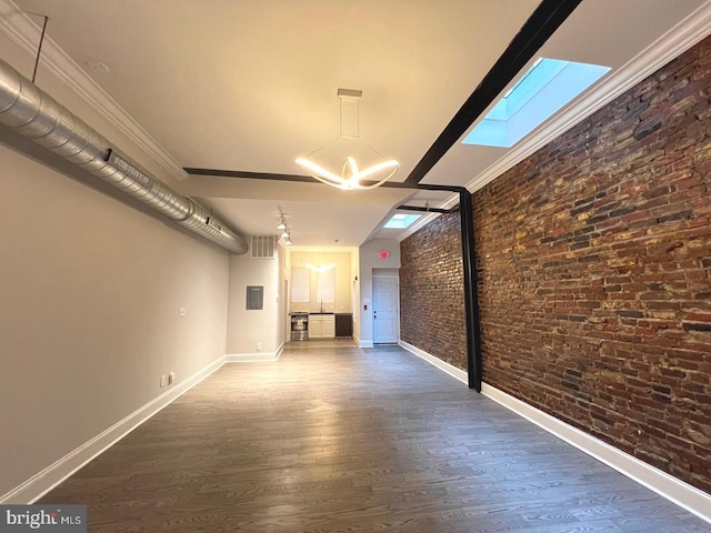 unfurnished living room with an inviting chandelier, brick wall, baseboards, and wood finished floors