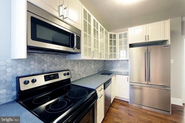 kitchen with dark wood-style flooring, a sink, white cabinets, glass insert cabinets, and appliances with stainless steel finishes