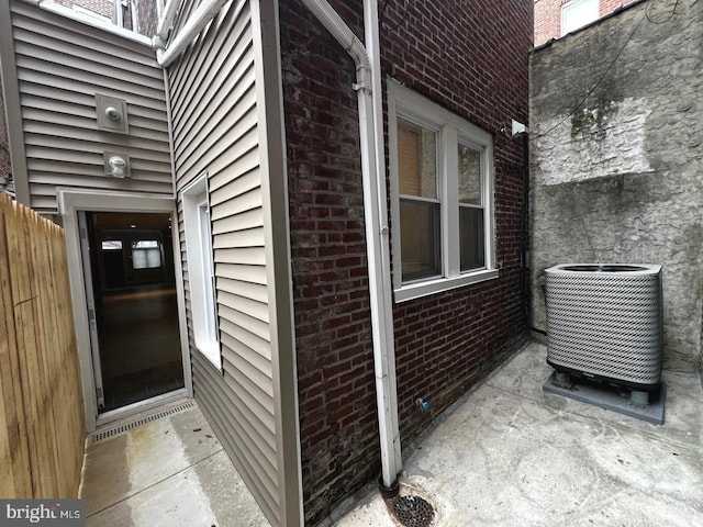 property entrance with brick siding and central AC unit