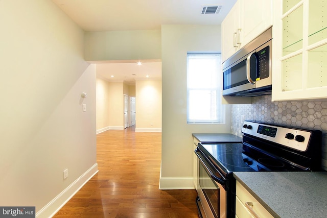 kitchen featuring visible vents, baseboards, decorative backsplash, wood finished floors, and stainless steel appliances